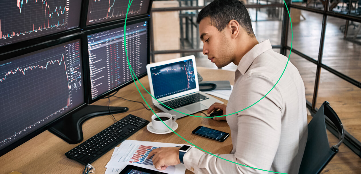 Trader analyzing financial data on multiple screens at a desk with charts, graphs, and a laptop, illustrating why forex traders need quantitative tightening.