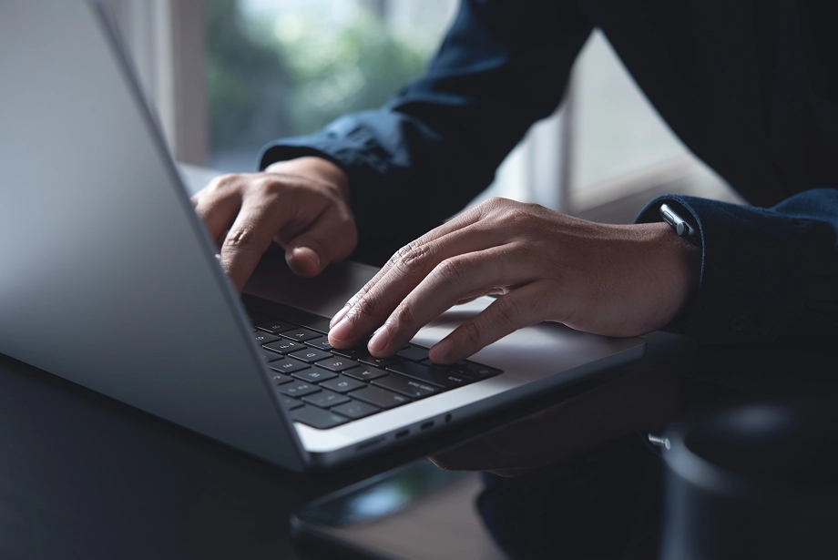 A person setting up their TradingView account on a laptop, focused on the screen with trading charts and interface visible.