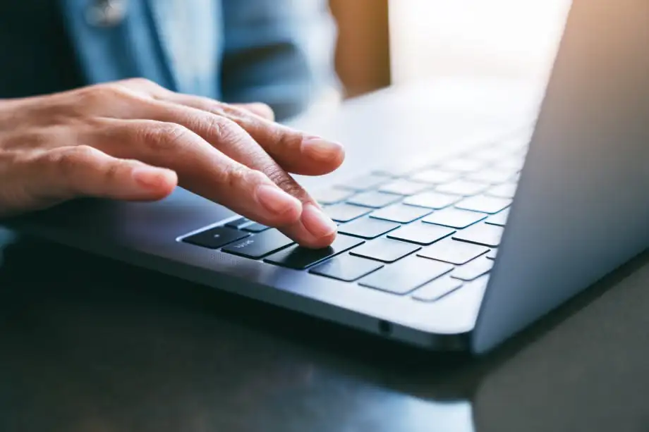 a trader’s hand pressing a key on a laptop keyboard, symbolizing fast one-click trading execution on MetaTrader 5