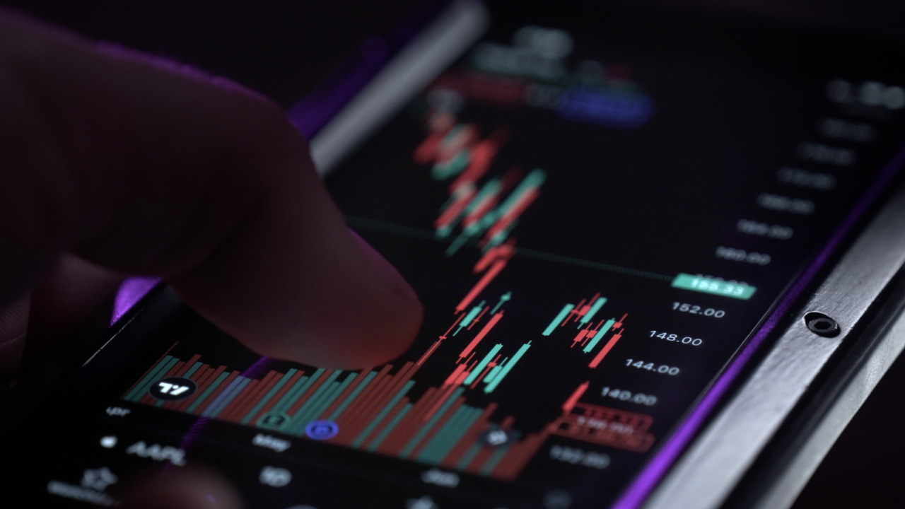 a hand interacting with a smartphone displaying a candlestick chart