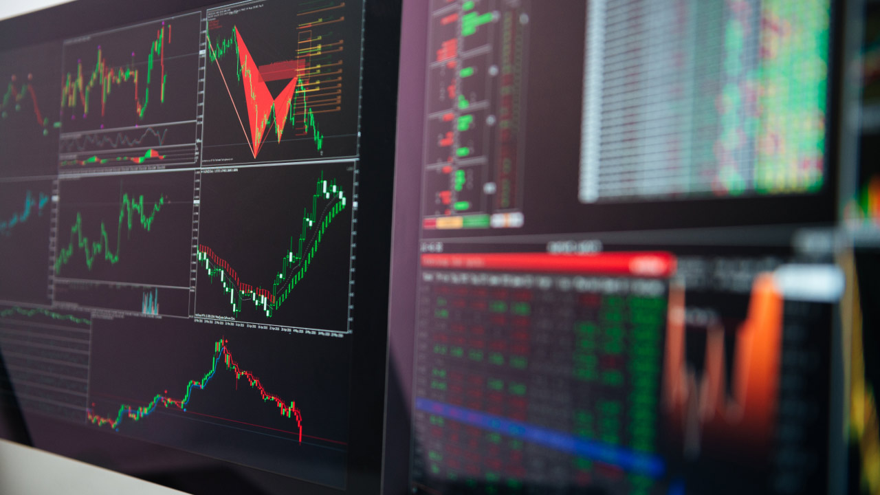 multiple trading charts on a monitor displaying technical analysis indicators