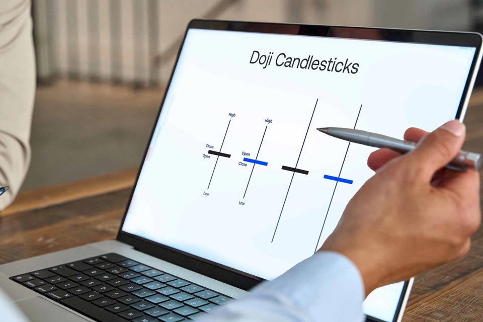 a person pointing at a laptop screen displaying a diagram of Doji candlestick patterns