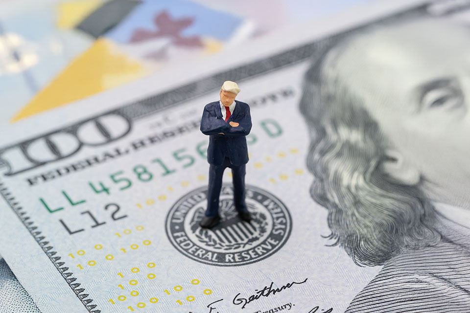 A miniature businessman figurine standing on a U.S. hundred-dollar bill, illustrating Forex Week Ahead Analysis: 27th January.