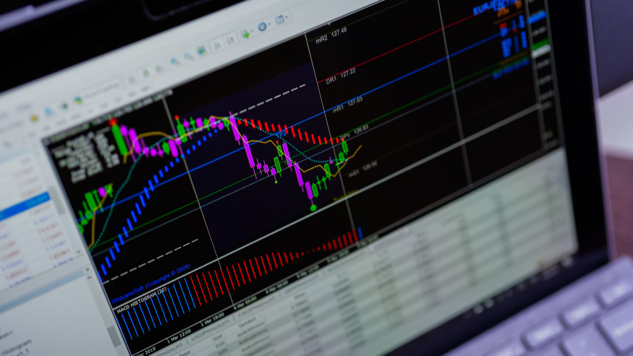 How to Download Historical Data on MT4, a trading platform displayed on a laptop screen, featuring colorful candlestick charts and technical indicators.
