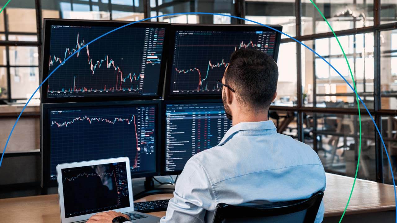 a trader sitting in front of multiple monitors displaying financial charts 