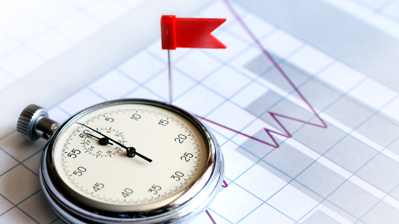 a stopwatch placed on a financial chart with a red flag pin marking a specific point