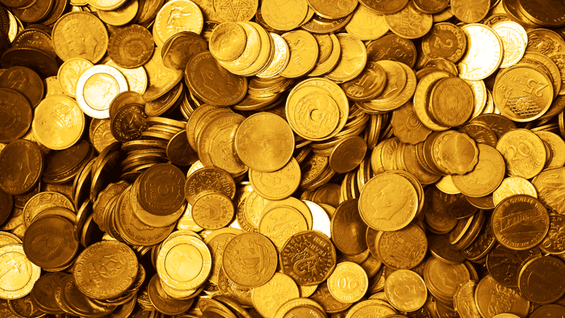 Pile of various gold-colored coins from different countries, symbolizing global currencies and wealth.