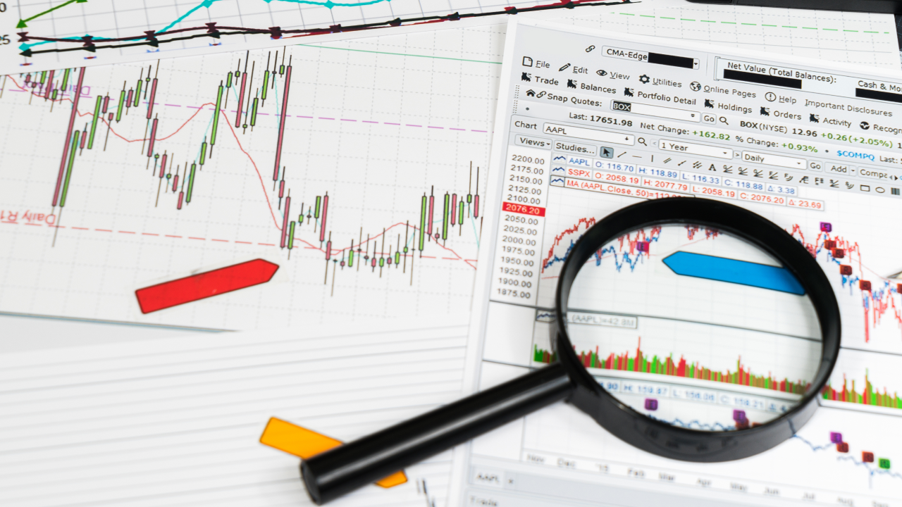 close-up of financial charts with candlestick patterns and trend lines and magnifying glass