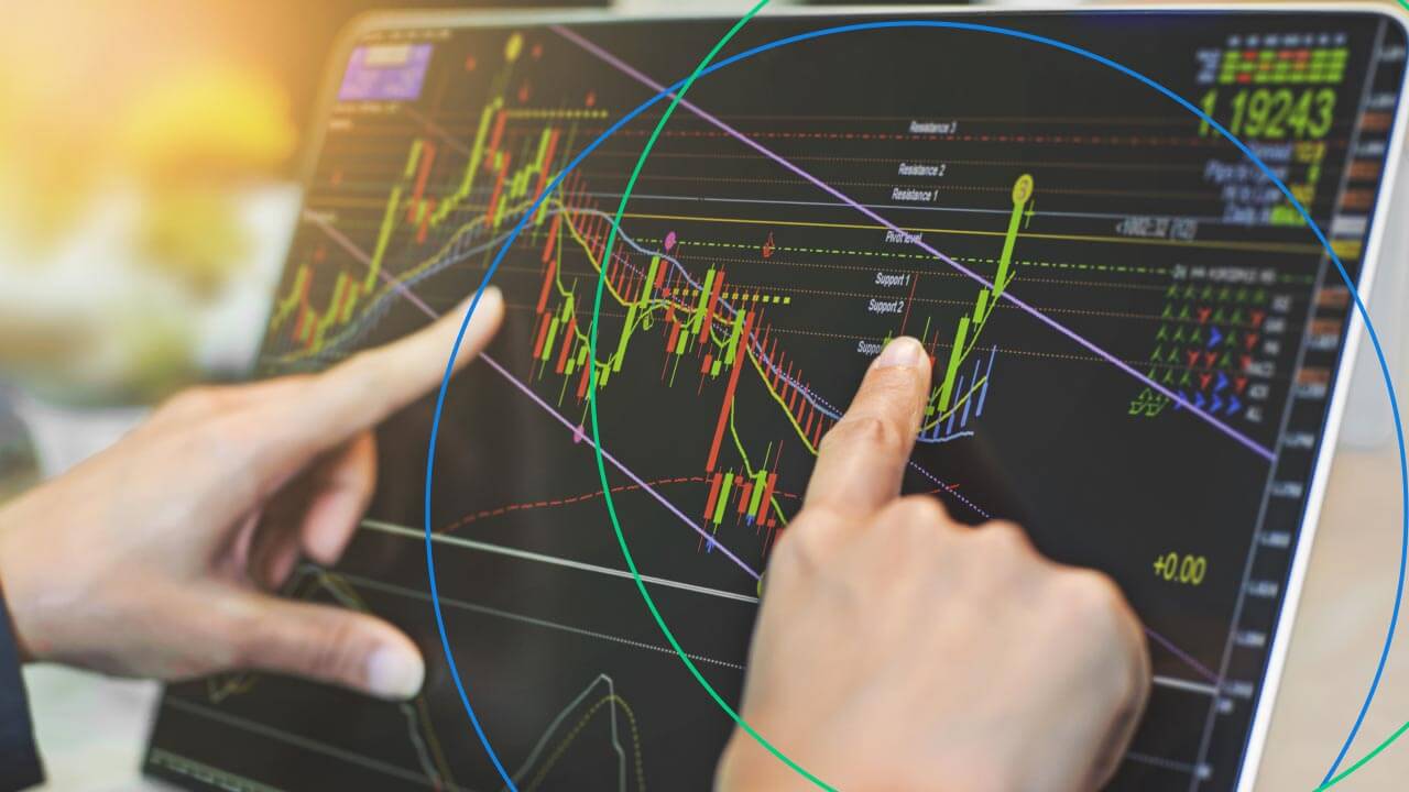 Hands pointing at a touchscreen displaying a colorful technical trading chart with candlesticks, trendlines, support and resistance levels, illustrating the concept of the key drivers of the Forex market.