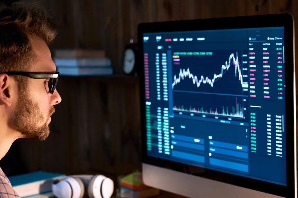 An image titled "Why Trade Forex?" showing a focused trader analyzing a forex trading platform displayed on a desktop monitor.