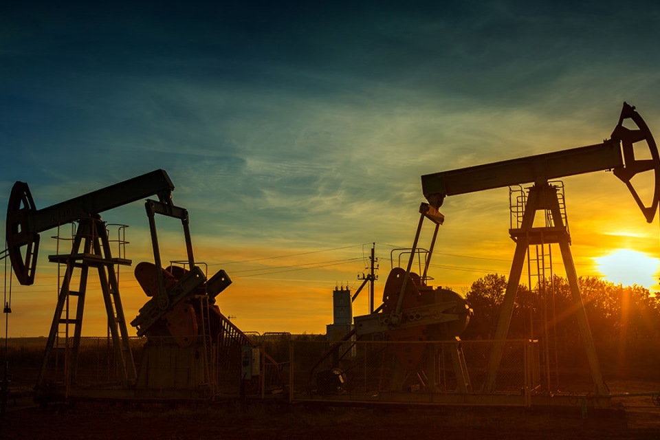 An oil field with pumpjacks operating at sunset, illustrating the relationship between oil prices and the stock market, as fluctuations in crude oil impact global financial markets, titled “How Do Oil Prices Affect the Stock Market?”