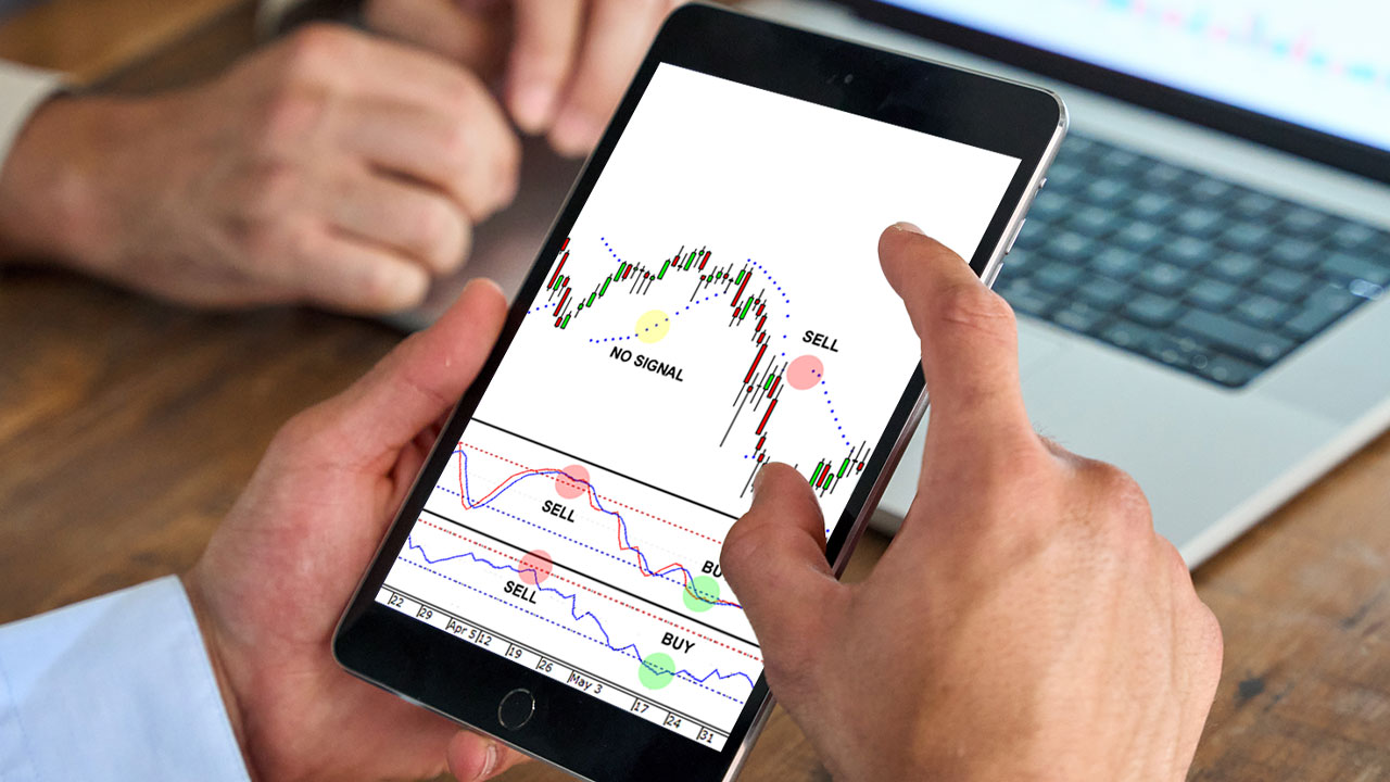 Custom Oscillators To Personalizing Your Trading a person holding a tablet displaying a forex trading chart with technical indicators on the screen.