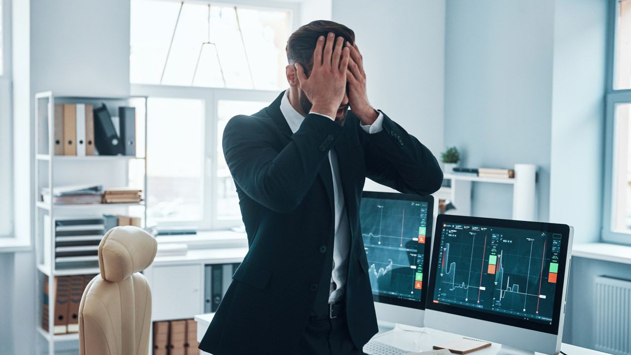 a frustrated businessman in a suit holding his head in distress