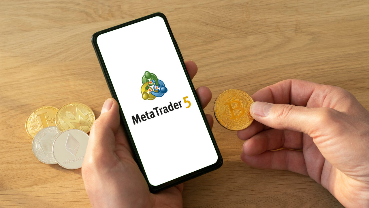  a person holding a smartphone with the MetaTrader 5 (MT5) logo and a Bitcoin