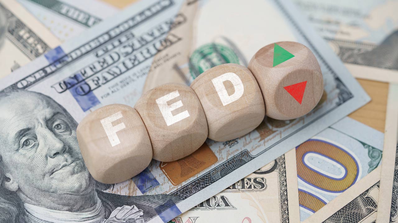 A Forex Trader's Guide to Federal Reserve Bank showing wooden blocks spelling "FED" placed on 100 US dollar bills.