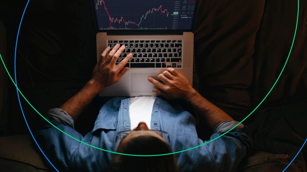 A person wearing a denim shirt is seen from above, sitting comfortably and using a laptop to monitor financial charts, illustrating "How to Become a Part-Time Forex Trader."