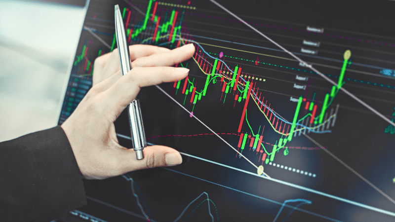 hand pointing at a laptop that shows some trades