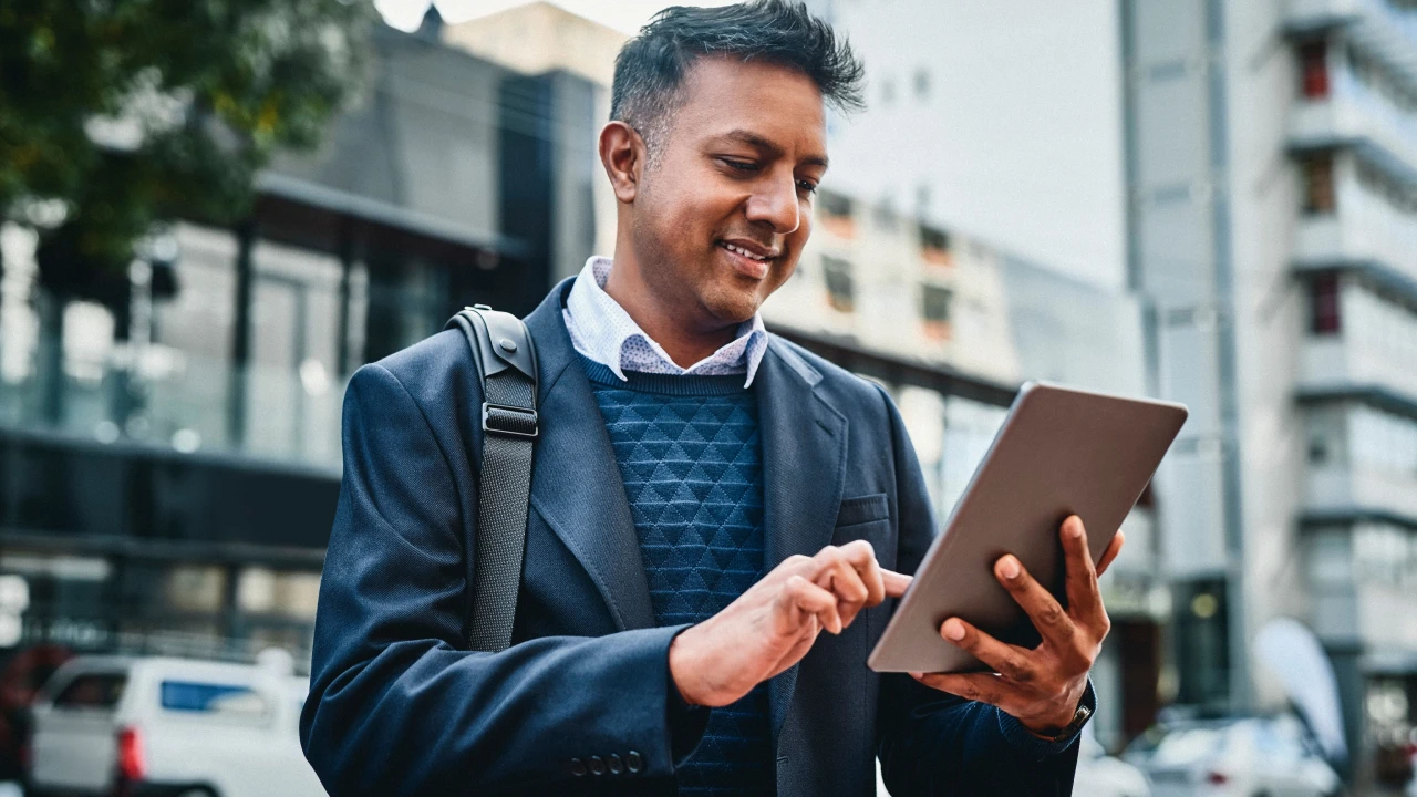 Man holding a tablet and trading, analyzing forex charts to identify top reversal patterns for forex trading.