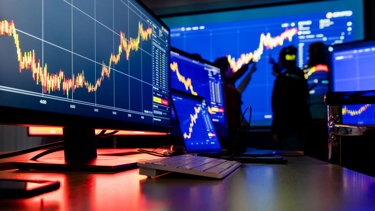 A modern trading setup with multiple monitors displaying various financial charts with candlestick patterns and trading data, illustrating the process of "How to Switch Forex Brokers."