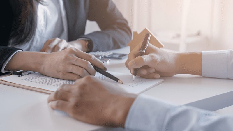 Close-up of two people sitting across a desk during a business meeting.