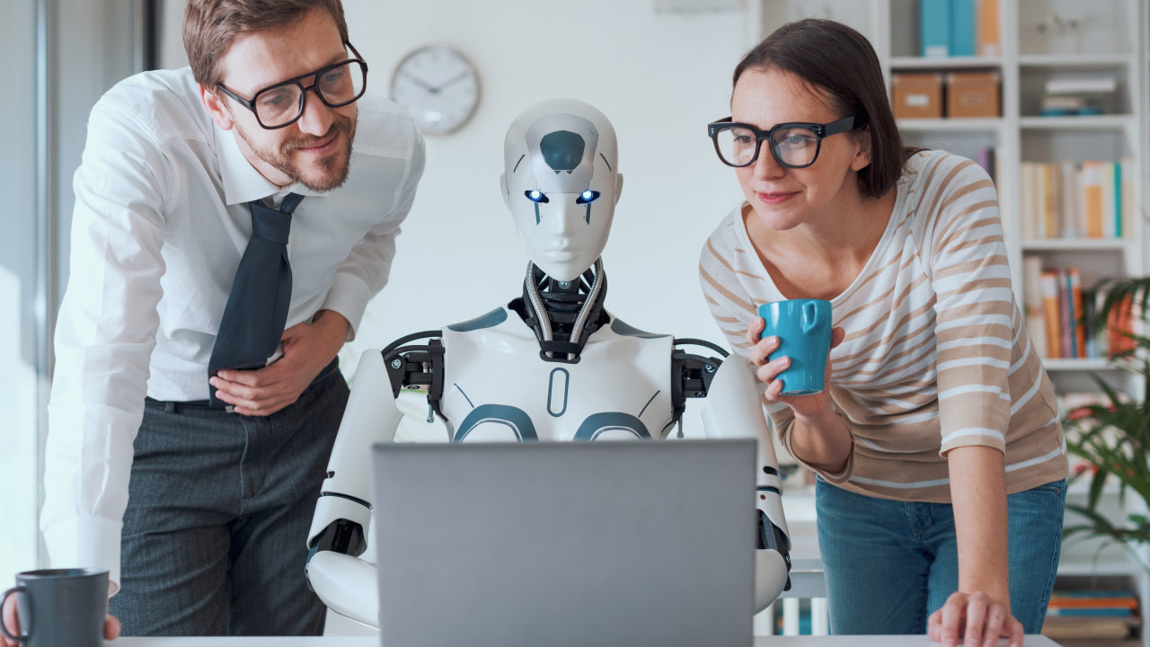 two professionals looking at a laptop screen with a humanoid robot