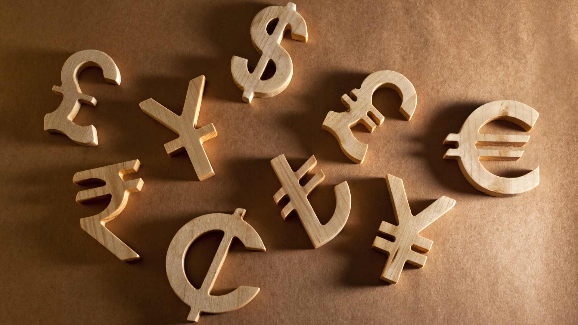 Choosing Forex Pairs: A Comprehensive Guide Wooden cutouts of various currency symbols, representing the diversity of forex pair options for traders.