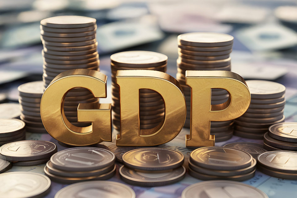 Golden GDP letters surrounded by stacks of coins, illustrating how traders can use GDP data to find trading opportunities.