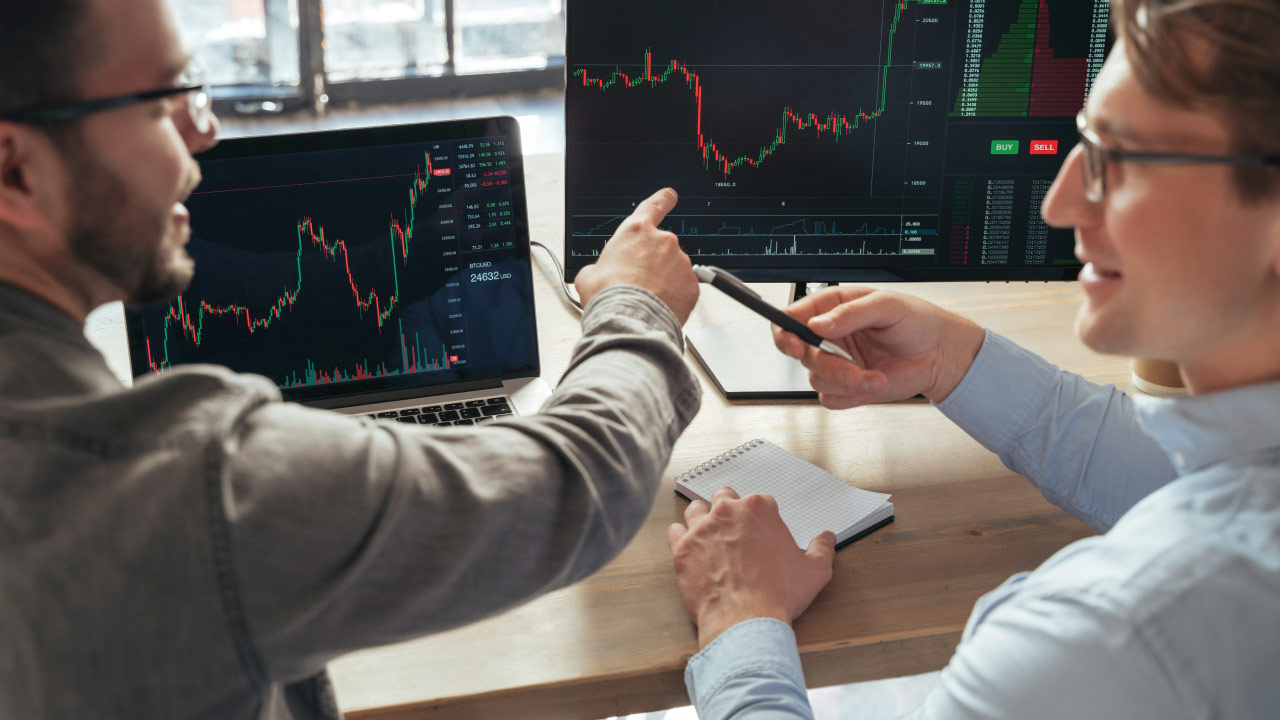 two traders discussing stock market trends while pointing at charts