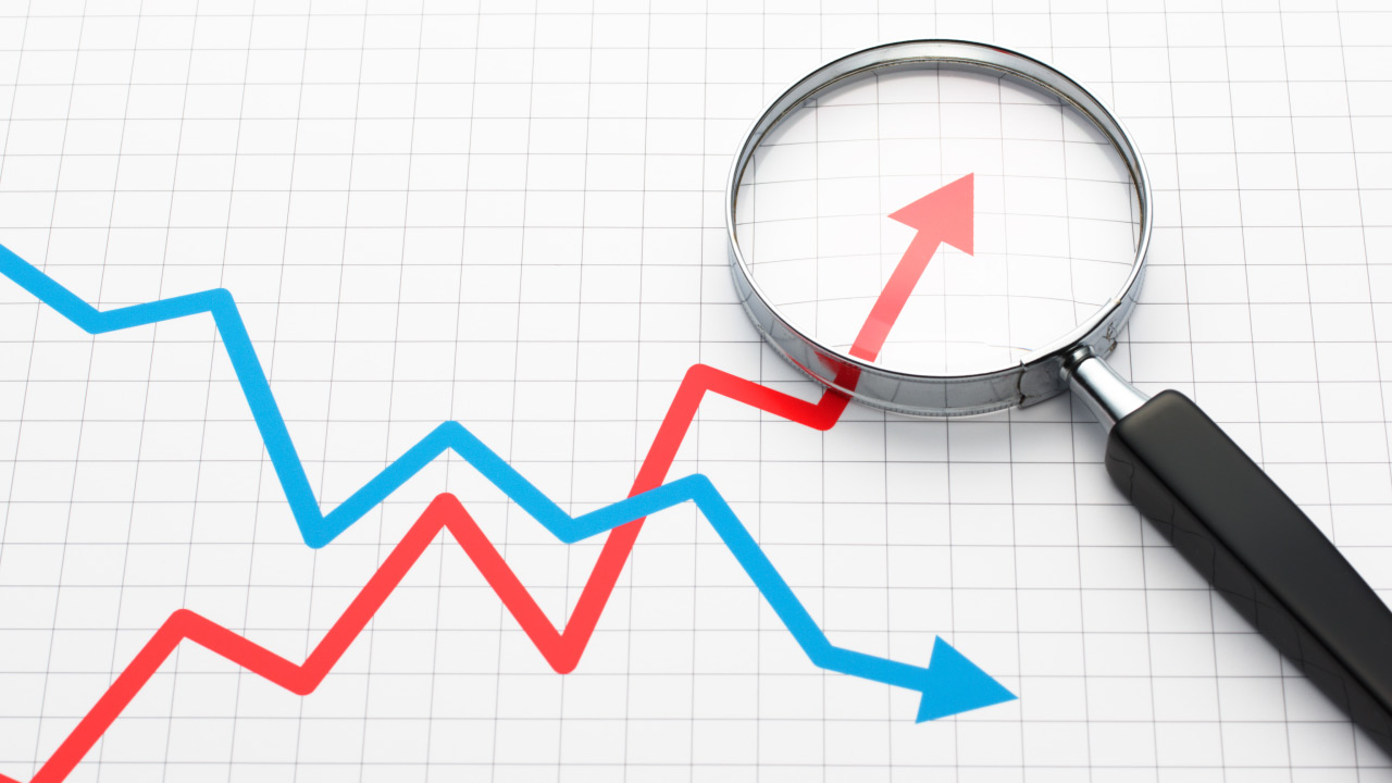 a magnifying glass focusing on a red upward trend line