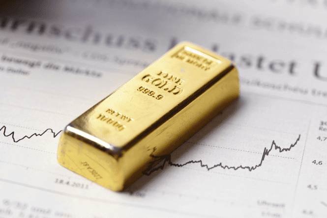 A gold bar labeled "999.9 FINE GOLD" lies on a financial newspaper displaying a rising price chart, illustrating the concept of "Gold Prices Falling After a Period of Strong Growth."