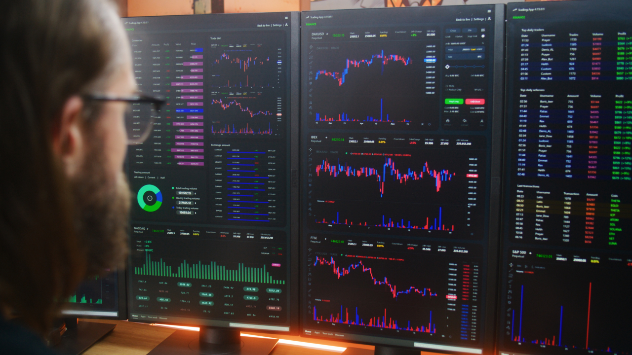 A trader analyzing financial charts and data on multiple monitors, illustrating the concept of multi-asset trading across forex, stocks, and commodities.