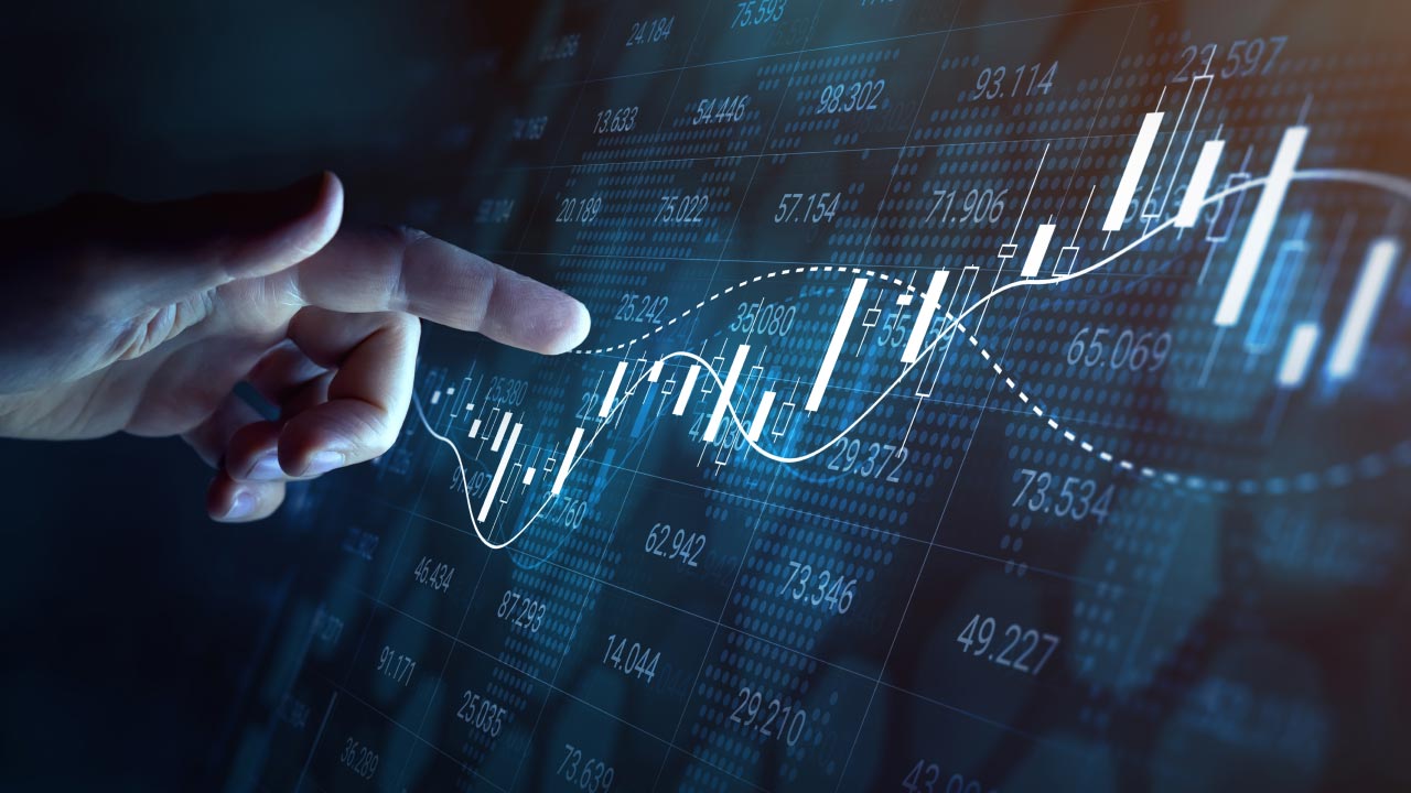 a hand interacting with a digital display of financial data, including candlestick charts